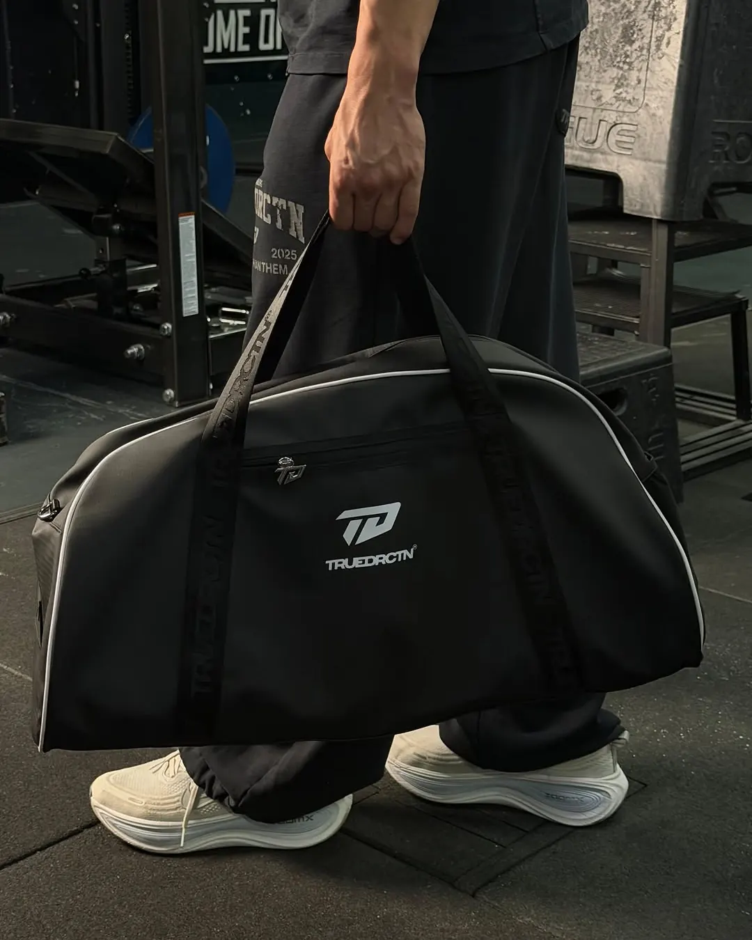 Schwarze True Direction Sporttasche in der Hand, Gymboden